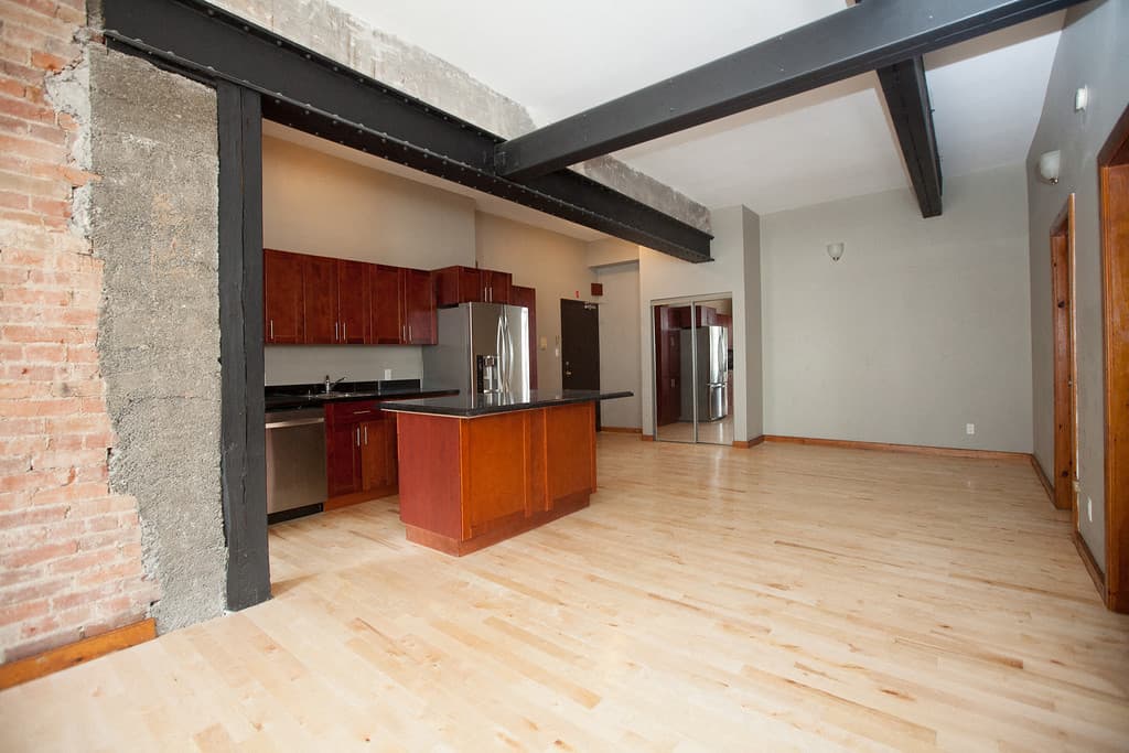 Open-plan suite with black steel beams across the ceiling and a kitchen island