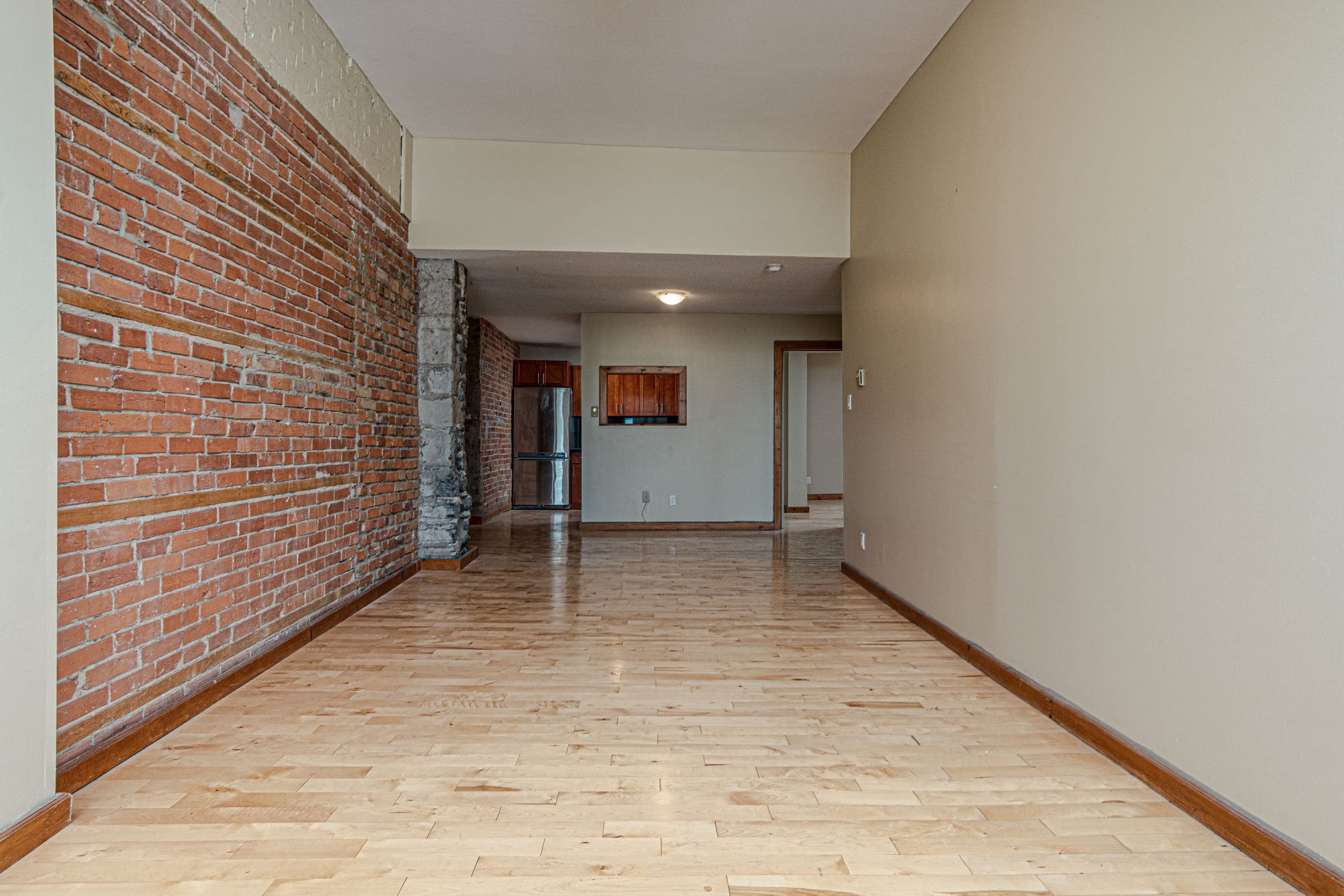 A long open living space at 265 Ontario, exposed brick down one wall and hardwood throughout